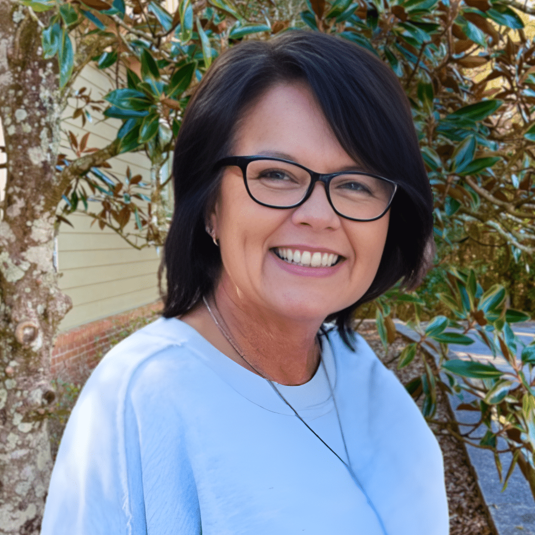a woman wearing glasses and smiling at the camera